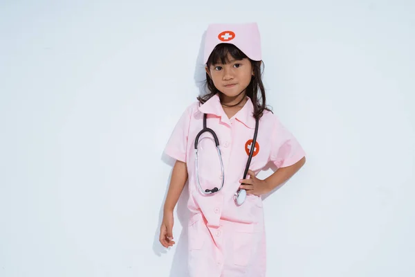 Cute asian little girl wearing doctor uniform with one hand on waist — Stock Photo, Image