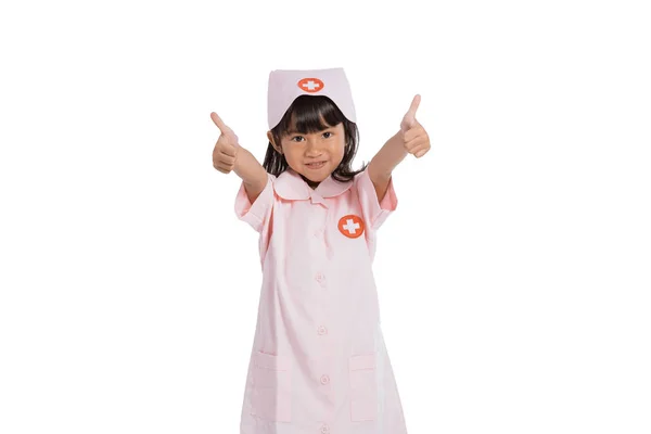 Liten flicka bär en sjuksköterska uniform med tummen upp händer gest — Stockfoto