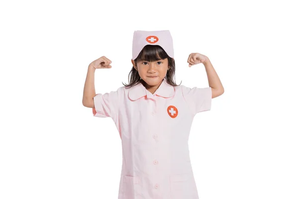 Little girl wearing a nurse uniform with showing muscles on arms — Stock Photo, Image