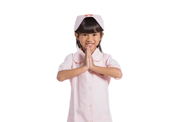 Asiatisches kleines Mädchen trägt eine Krankenschwesteruniform mit beiden Händen vor der Brust — Stockfoto