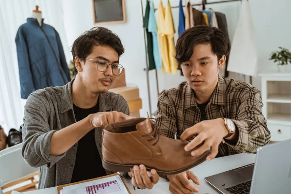 Két fiatal ázsiai üzletember beszélget a termékükről. — Stock Fotó