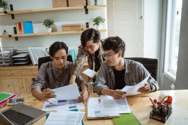 Üç genç Asyalı işadamı ürünleri hakkında konuşuyor.