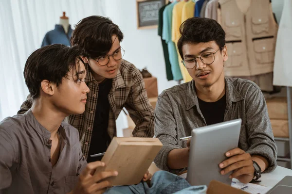 Három fiatal ázsiai üzletember beszélget a ruházati termékek csomagolásáról — Stock Fotó