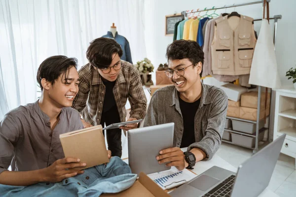 Trois jeunes homme d'affaires asiatique bavarder sur l'emballage de leur produit vestimentaire — Photo