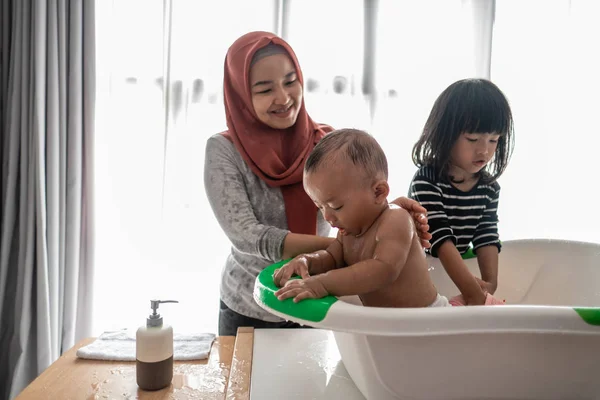 Adik membantu ibunya untuk mencuci adik bayi — Stok Foto