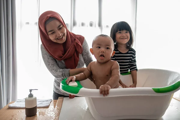 Bebé niño feliz tomando un baño con la madre y la hermana —  Fotos de Stock