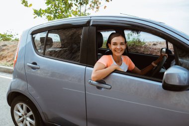 Kadın arabasında otururken gülümsüyor.