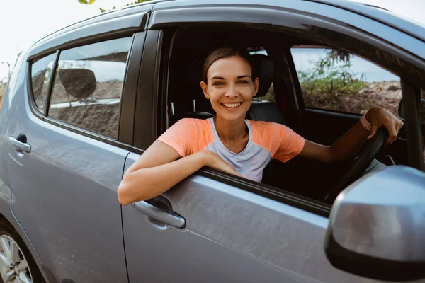 Mujer sonriendo mientras está sentada en su coche —  Fotos de Stock