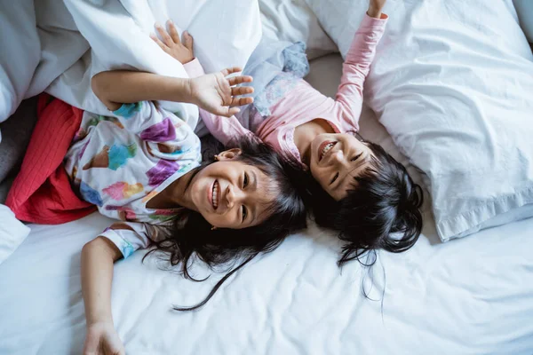 Dvě děti si hrají a smějí se v posteli — Stock fotografie