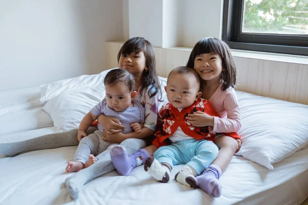 Cuatro niños felices de jugar y bromear en la cama —  Fotos de Stock