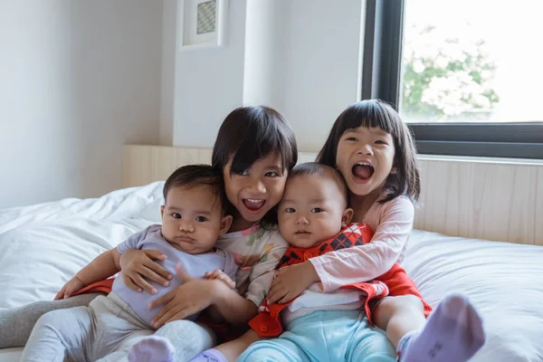 Quatre enfants heureux de jouer et de plaisanter au lit — Photo