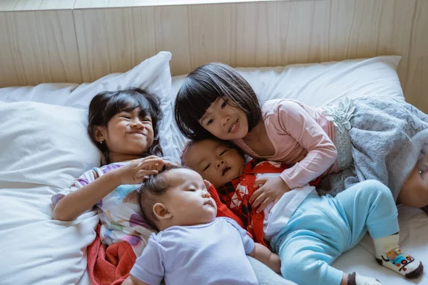 Cuatro niños felices de jugar y bromear en la cama —  Fotos de Stock