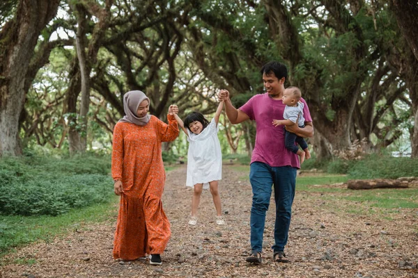 Vater und Mutter heben die Hände ihrer Töchter und tragen das Kind beim Gehen — Stockfoto