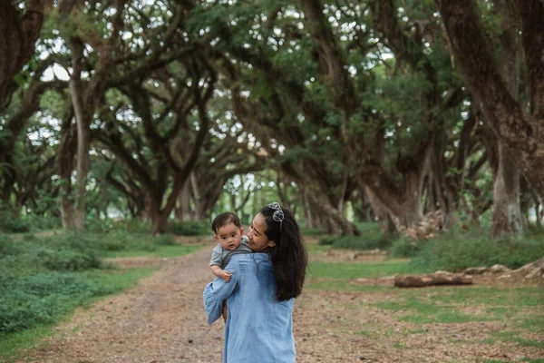 Mãe está carregando seu bebê enquanto caminha — Fotografia de Stock