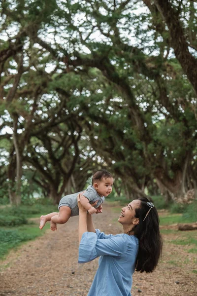 Asiático madre risas mientras sosteniendo hasta un bebé — Foto de Stock