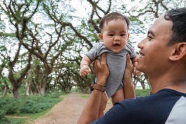 Babam kucağında bir bebekle güler.