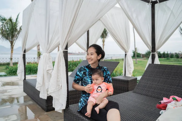 Asian mother holds the baby sitting on her lap while sitting — Stock Photo, Image