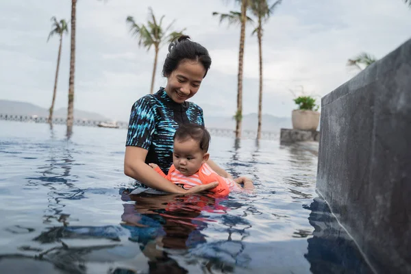 Mãe segura seu bebê enquanto aprende a nadar — Fotografia de Stock