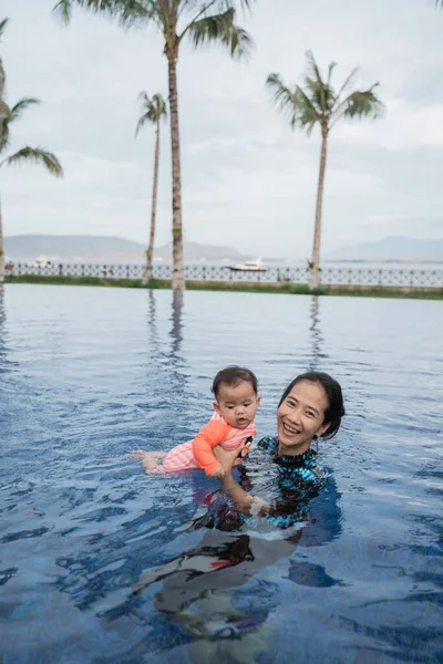 Mãe segura seu bebê enquanto aprende a nadar — Fotografia de Stock