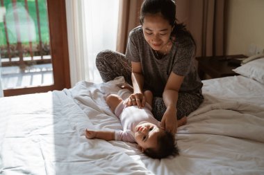 Anne küçük kızını tutarak şaka yapıyor.