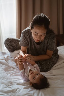 Anne küçük kızını tutarak şaka yapıyor.