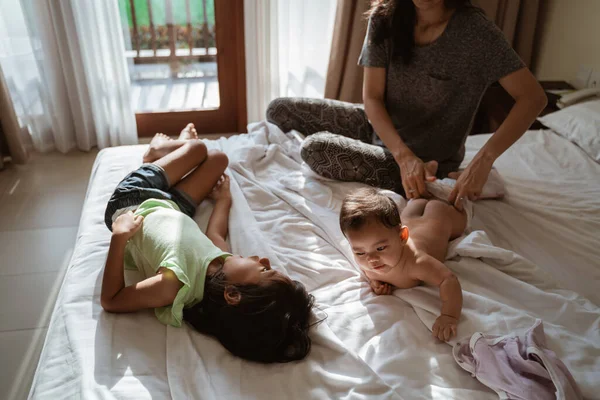 Anne bebeğine kıyafet giyiyor.