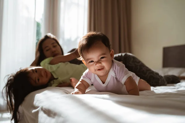 Asiática poco niños acostado en cama con su madre al lado de ellos — Foto de Stock