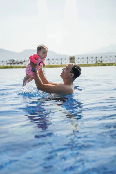 Ásia pai pega até seu filhas bebê quando aproveitando natação — Fotografia de Stock