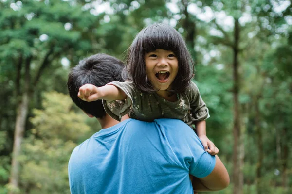 Bambina rise felicemente quando portato sulla spalla dei suoi padri — Foto Stock