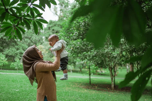 Schattig baby glimlach wanneer zijn moeder til hem op — Stockfoto