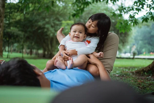 Two daughters happily sitting on a fathers stomach — Stock Photo, Image