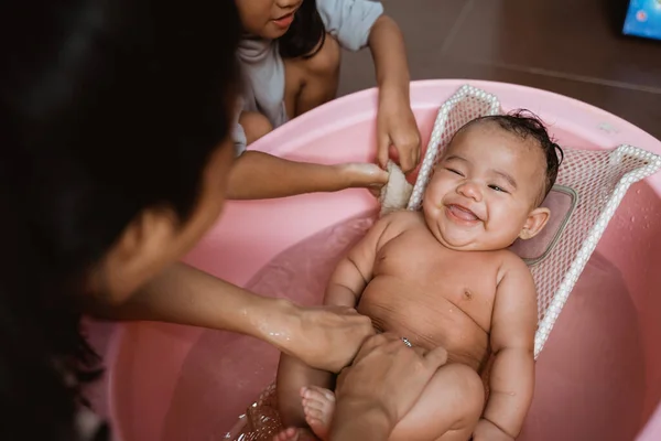Adorable bebé teniendo baño con madre y hermana —  Fotos de Stock