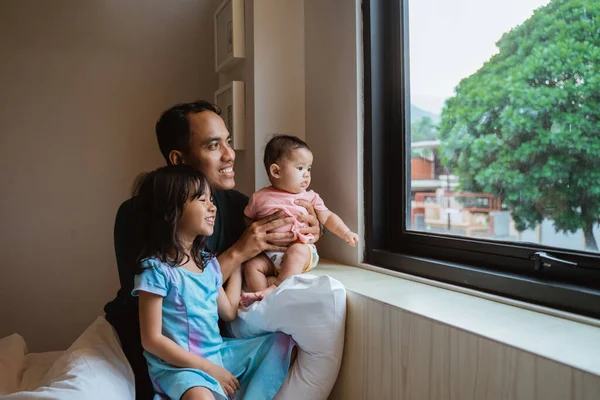 Vater und zwei kleine Tochter sehen aus dem Fenster — Stockfoto