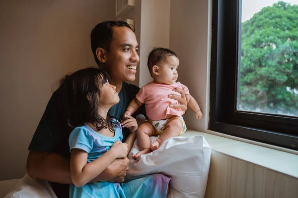 Asiático padre y dos poco hija viendo fuera de la ventana vidrio —  Fotos de Stock