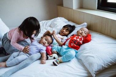 Yatakta şakalaşmaktan mutlu dört çocuk.