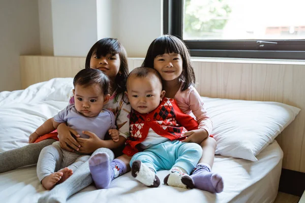 Čtyři asijské děti úsměv, když sedí na posteli — Stock fotografie