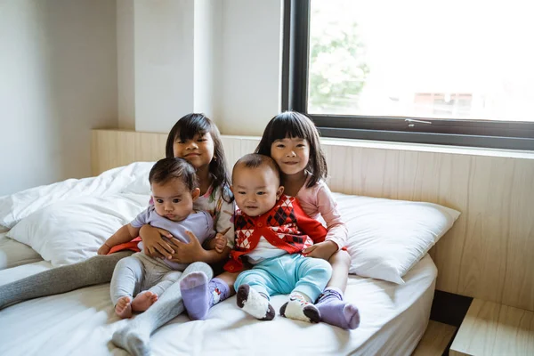 Quatro crianças sorriem quando sentadas na cama — Fotografia de Stock