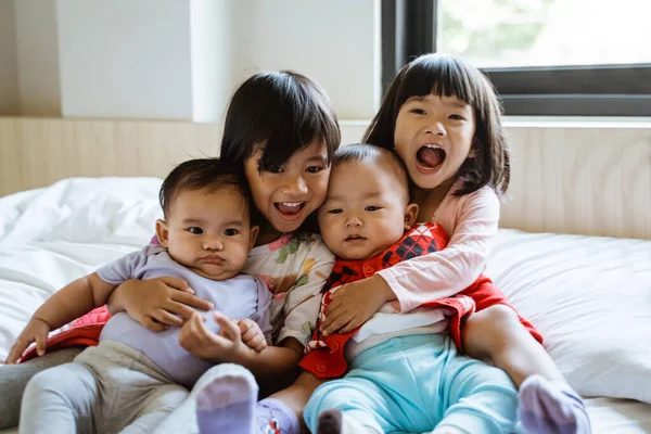 Cuatro niños asiáticos se ríen mientras están sentados en la cama —  Fotos de Stock