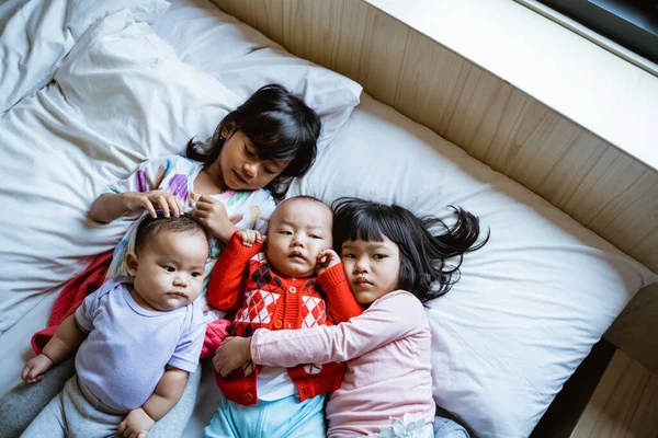 Čtyři děti leží v posteli a objímají se — Stock fotografie