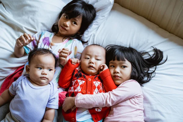 Quatro asiático crianças mentira no cama abraçando cada outros — Fotografia de Stock