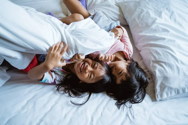 Två barn leker och skrattar i sängen — Stockfoto