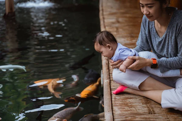 Asian mother and her baby daughter see koi fish — Stock Photo, Image