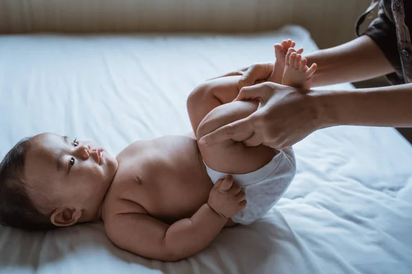 Mère étirer ses pieds de bébé sur le lit — Photo