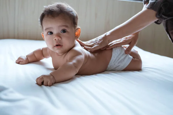 Bebé propenso se frota la espalda por su madre —  Fotos de Stock