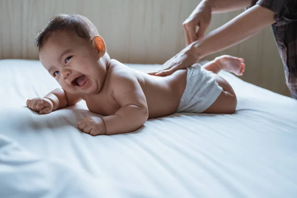 Bebé propenso feliz es frotado su espalda por su madre —  Fotos de Stock