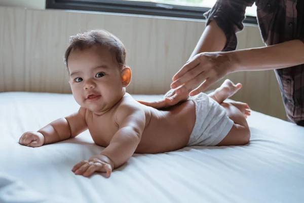 Bebé propenso se frota la espalda por su madre —  Fotos de Stock