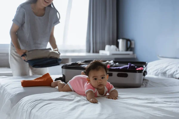 Baby liegt auf dem Bett neben einem gefüllten Koffer — Stockfoto