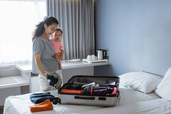 Mãe segurando sua menina enquanto prepara roupas — Fotografia de Stock