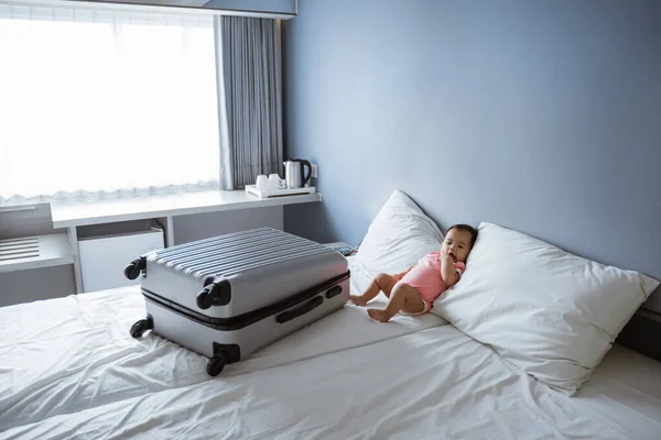 3.宝宝躺在大手提箱旁边的床上 — 图库照片