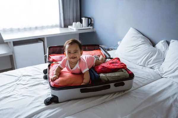 Bebê ri em seu estômago em uma mala aberta — Fotografia de Stock